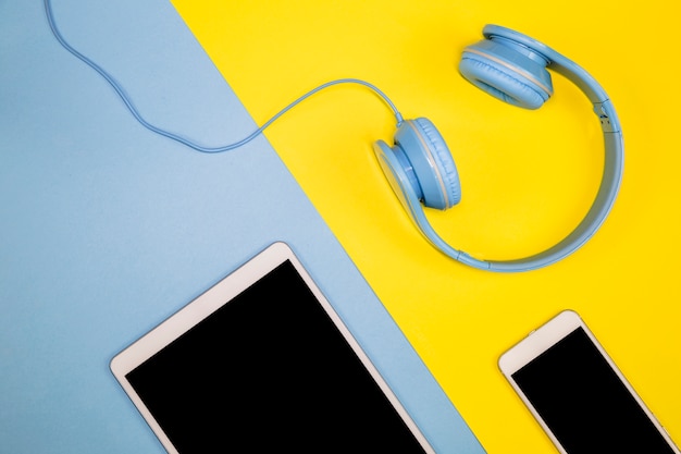 Smartphone with tablet and headphones on table