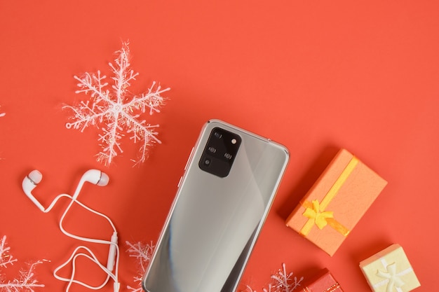 Смартфон с тремя камерами и рождественским декором на красном фоне