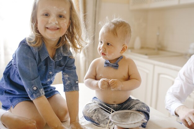 小さな男の子と女の子がテーブルの上に座ってまみれて