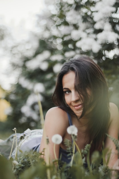 Smiled attractive woman is looking straight and lying on the green grass