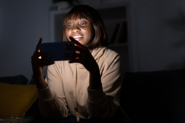 Foto gratuita donna afroamericana sorridente che guarda il servizio di streaming a casa