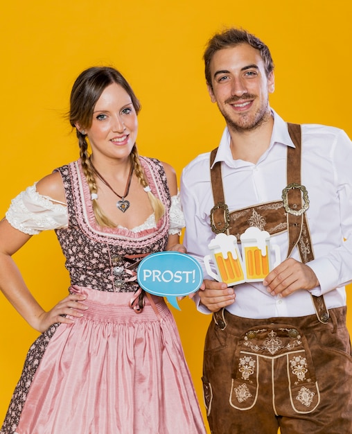 Free photo smiley bavarian couple holding oktoberfest signs