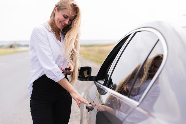 車のドアを開くスマイリーの美しい女性