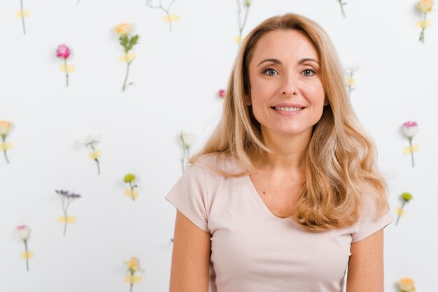 Smiley beautiful woman with floral wall