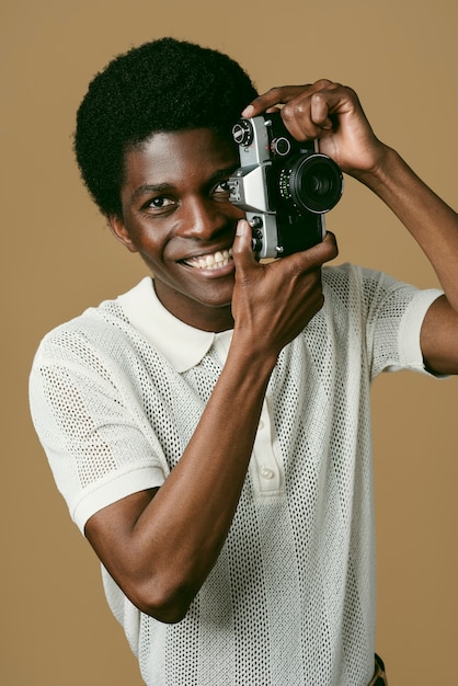 사진 카메라 중간 샷을 들고 웃는 흑인 남자