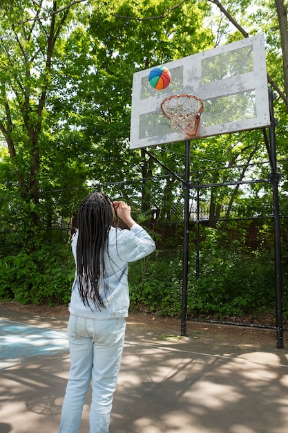 Free photo smiley black teenage girl playing basketball