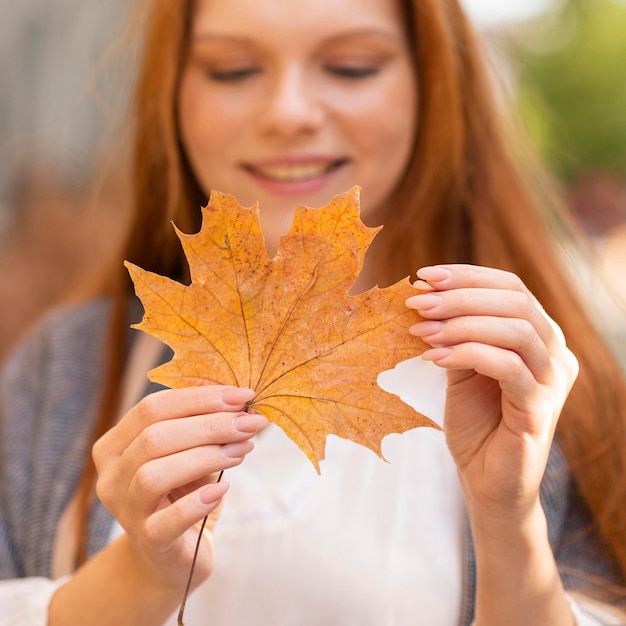 Free photo smiley blurred woman holding leaf