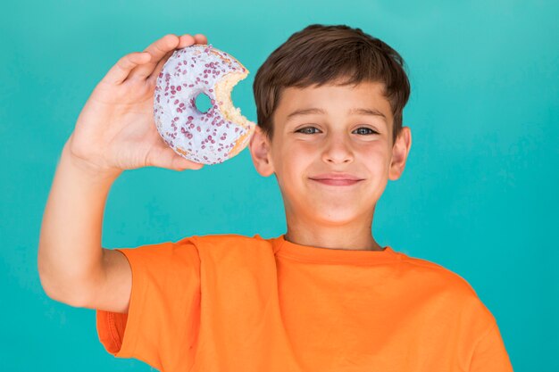 Улыбающийся мальчик держит глазированный пончик