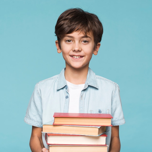 Smiley boy holding stack of books