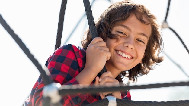 Foto gratuita ragazzo di smiley che gioca all'aperto mentre fuori con i suoi genitori