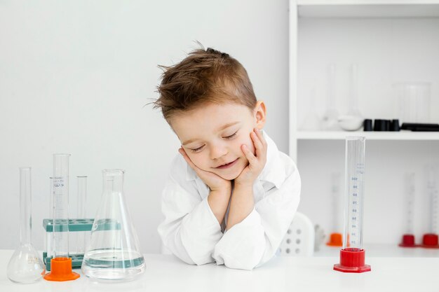 Smiley boy scientist in the laboratory with test tubes learning about science