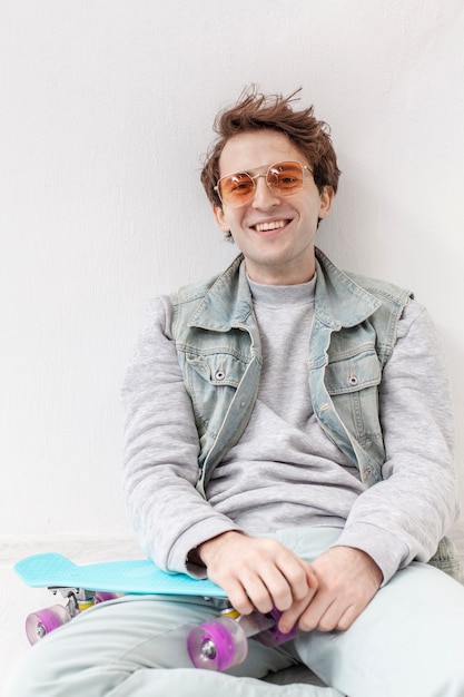 Smiley boy sitting with skateboard beside