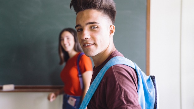 Free photo smiley boy with backpack and blurred girl at the backgroud