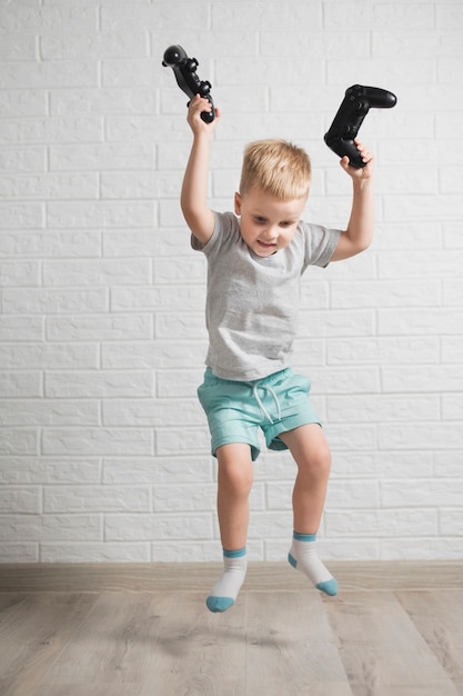 Smiley boy with joysticks in hand jumping