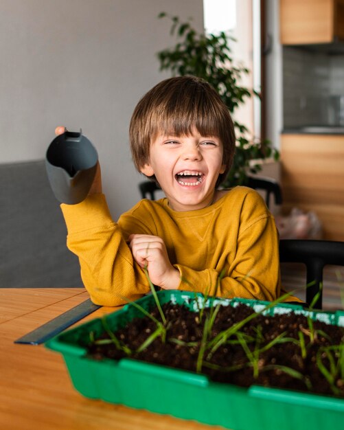 Smiley boy with watering can and crops at home