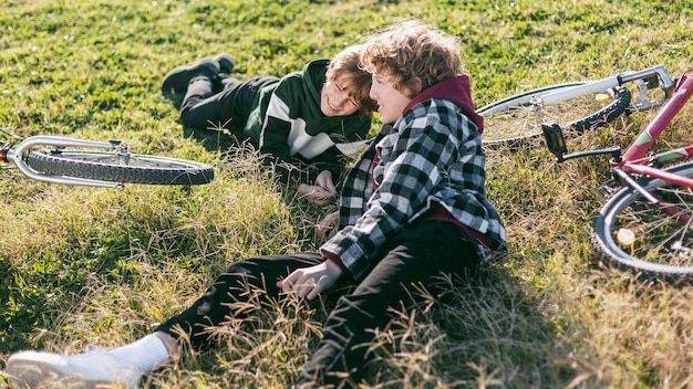 Smiley boys resting on grass while riding their bikes