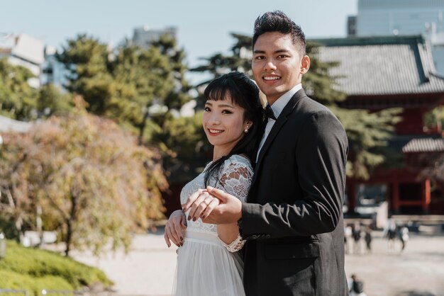 Smiley bride and groom posing together outdoors