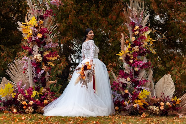 Улыбающаяся невеста позирует с цветами, вид сбоку