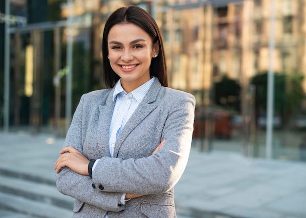 Smiley businesswoman posing outdoors with arms crossed and copy space