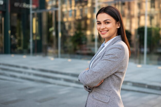 Smiley businesswoman posing outdoors with arms crossed