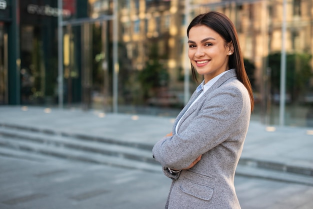 Smiley businesswoman posing outdoors with arms crossed