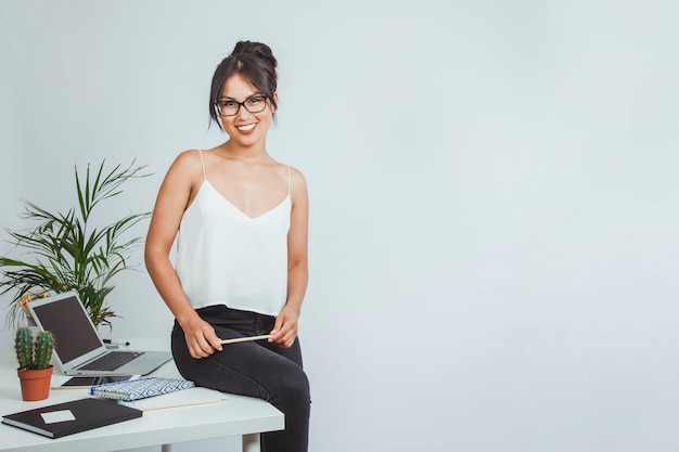 Free photo smiley businesswoman posing sitting on her desk