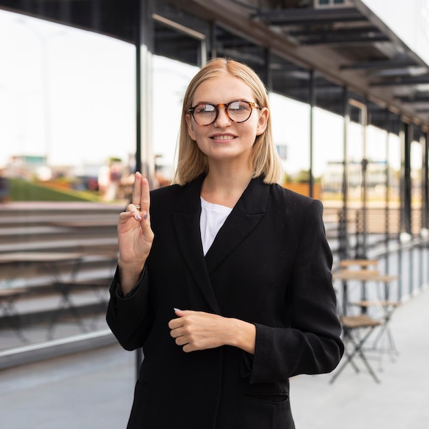 Смайлик бизнесвумен, используя язык жестов на открытом воздухе на работе