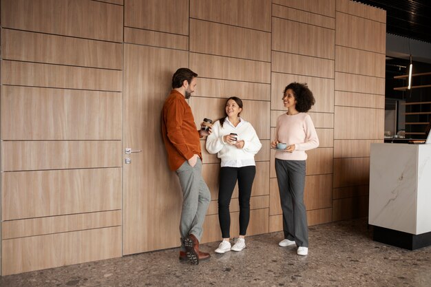 Smiley colleagues chatting at work full shot