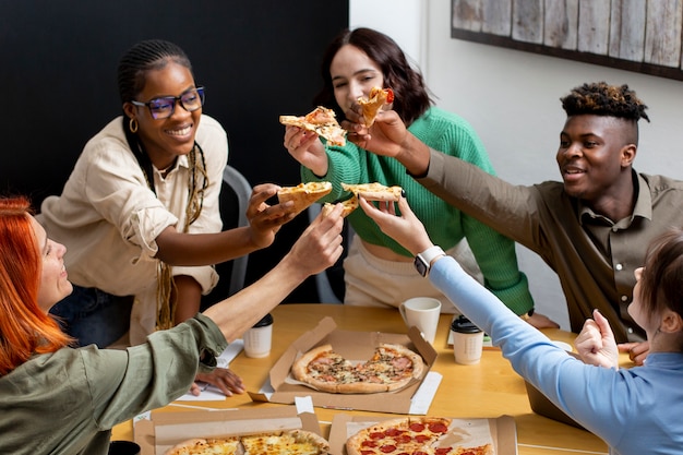 Улыбающиеся коллеги едят пиццу на работе