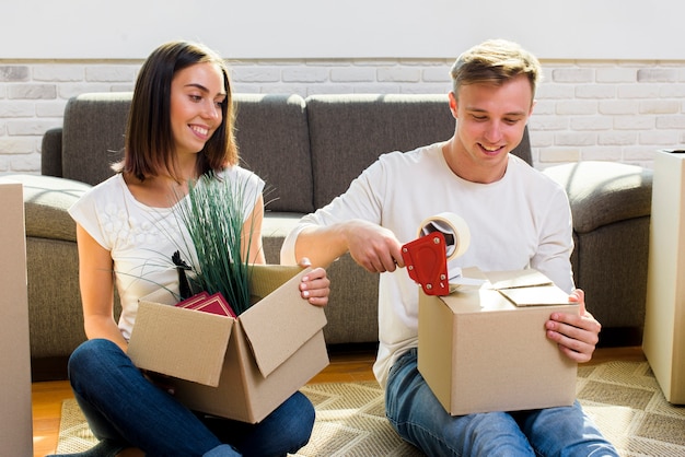 Free photo smiley couple bounding cardboard boxes