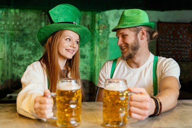 Smiley couple celebrating st. patrick's day at the bar with drinks