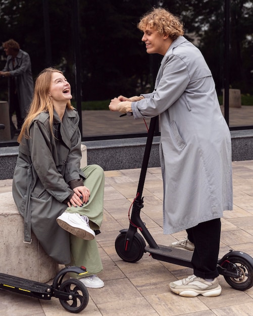 Smiley couple conversing outdoors with electric scooters