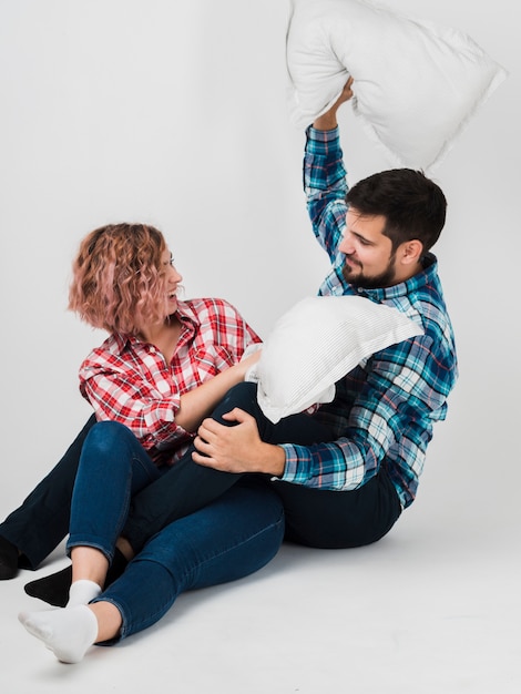 Smiley couple having a pillow fight