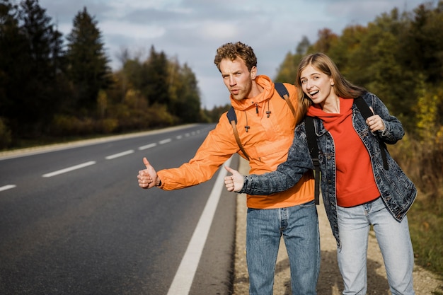 Smiley couple hitchhiking while on a road trip