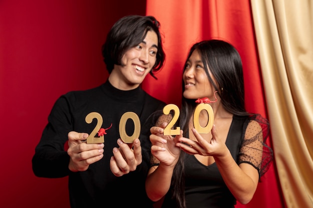 Free photo smiley couple holding new year sign and rat figurines