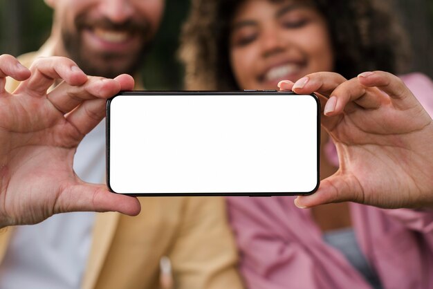 Smiley couple holding smartphone while camping outdoors