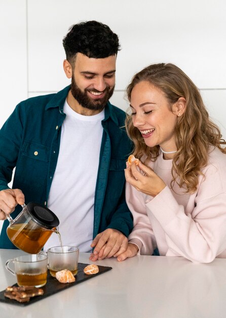 Smiley couple making tea at home together