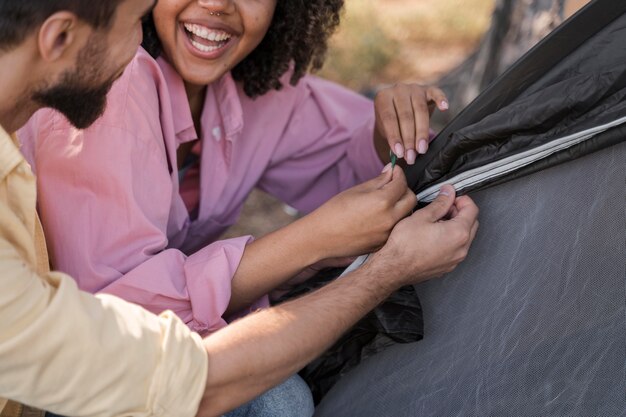 Smiley couple outdoors setting tent