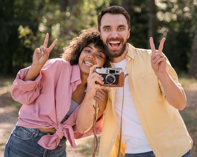 Free photo smiley couple outdoors taking pictures with camera