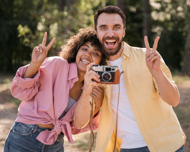 Smiley couple outdoors taking pictures with camera