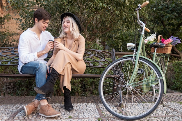 Foto gratuita coppie di smiley al parco bevendo caffè sul banco