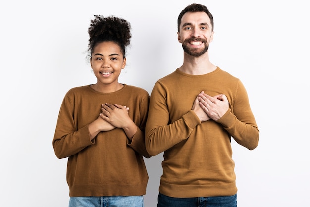 Smiley couple posing while holding chest