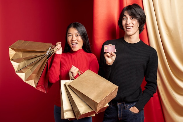 Free photo smiley couple posing with bags for chinese new year