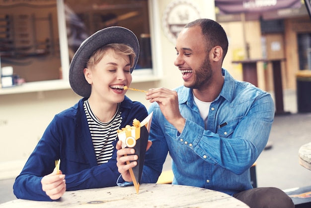 Free photo smiley couple sharing fast food