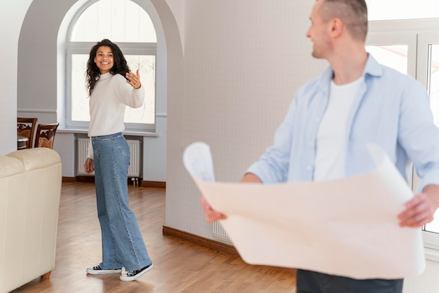 Smiley couple in their new home holding house plans