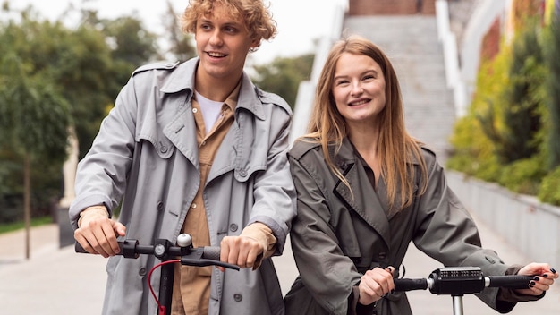 Smiley couple using electric scooter outdoors