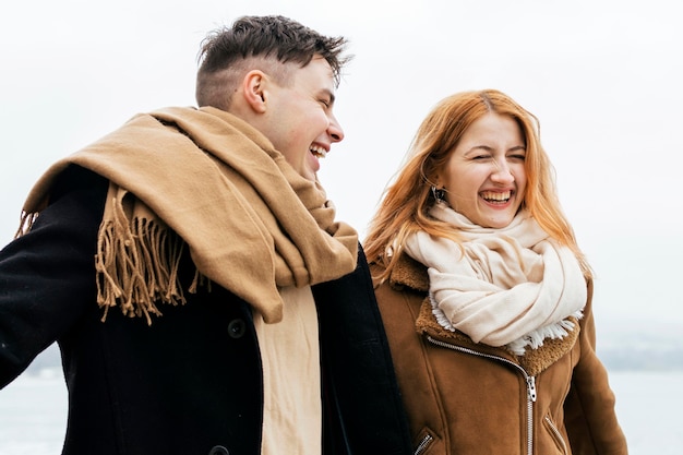 Smiley couple walking by the lake during winter