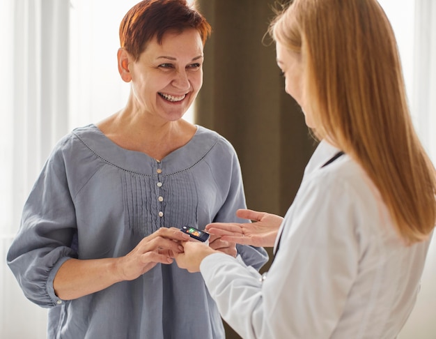 Smiley covid centro di recupero medico femminile che controlla il livello di ossigeno del paziente anziano