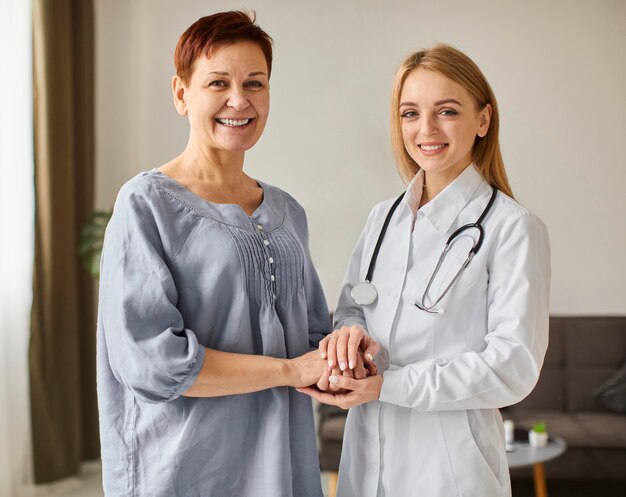 Smiley covid recovery center female doctor holding elder patient's hands