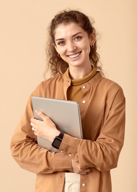 ノートパソコンを持っているスマイリー巻き毛の女性